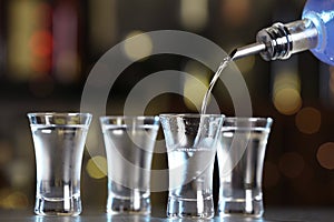 Pouring vodka from bottle into shot glass on counter