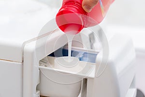 pouring the washing conditioner in the washing machine to get clean cloth