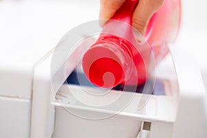 pouring the washing conditioner in the washing machine to get clean cloth