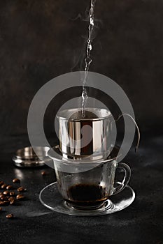 Pouring water in drip filter for cooking Vietnamese coffee.