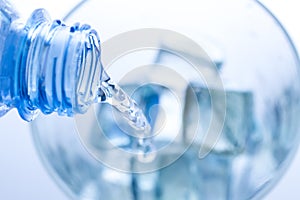 Pouring water in an elegant glass with ice and water drops.