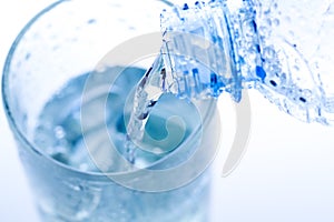 pouring water in an elegant glass with ice and water drops