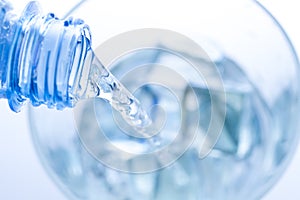 Pouring water in an elegant glass with ice and water drops.