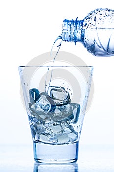 Pouring water in an elegant glass with ice and water drops