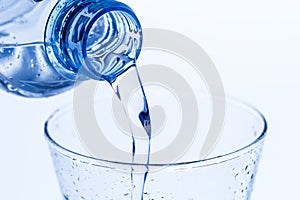 Pouring water in an elegant glass water drops on white background