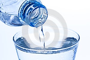 Pouring water in an elegant glass water drops on white background