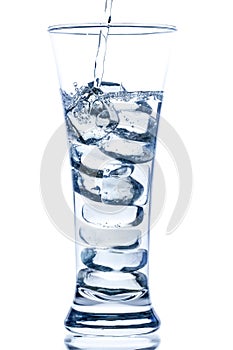 pouring water in an elegant tall glass with ice and water drops