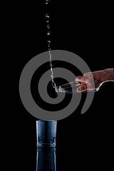 Pouring water on a glass on black background gravitation, gravity