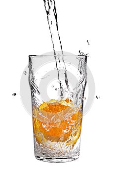 Pouring water into glass with orange slice