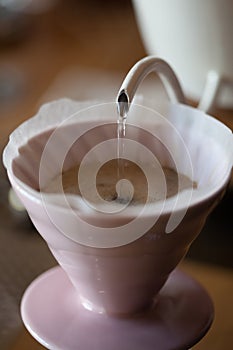Pouring water from kettle into glass pour over on scales closeup