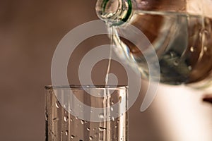 Pouring water from plastic bottle into a glass on blurred background. Selective focus and copy space