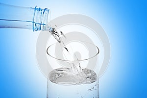 Pouring water from plastic bottle into glass on white background