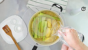 Pouring water in a pot with raw vegetables. Creamy pureed celery soup