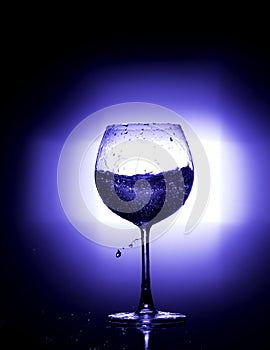 Pouring water into wine glass with black background blue white balance