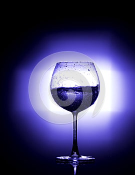 Pouring water into wine glass with black background blue white balance