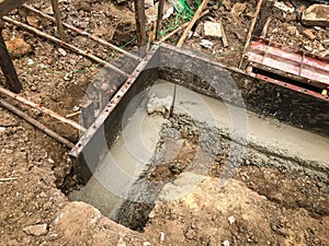 Pouring wet concrete in to a house foundation construct