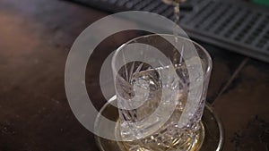 Pouring a whiskey cocktail into glass, close up. Alcohol pouring.