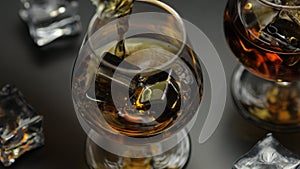 Pouring whiskey, cognac into glass. Black background. Pour of alcohol drink