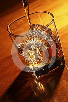 Pouring whiskey in glass with ice