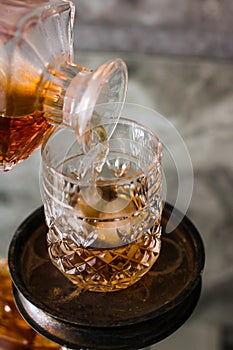 Pouring whiskey in glass with ice. Dammed glass with strong alcoholic drink