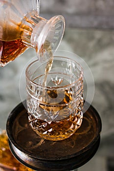 Pouring whiskey in glass with natural ice. Dammed glass