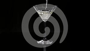 Pouring white martini in a cocktail glass - a classic drink