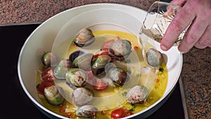 Pouring white wine while cooking spaghetti alle vongole clams