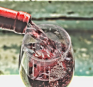 Pouring wine. Red wine in a glass. Sommelier wine into the glass on a blue background old.