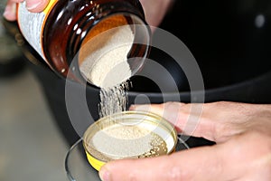 Pouring yeast grains to make bread into a glass