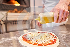 Pours olive oil. Baked tasty margherita pizza in Traditional wood oven in Naples restaurant, Italy. Original neapolitan