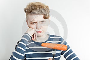 Pouting boy with fork stuck in carrot