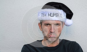 Pouting Caucasian man in a black and white Bah Humbug hat