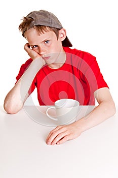 Pouting child behind white cup