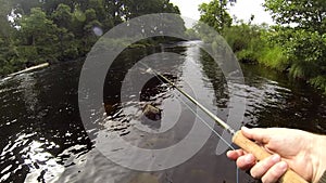 POV of an angler holding a salmon fly rod and line while fishing on a River