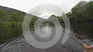 POV of an angler holding a salmon fly rod and line while fishing on the river