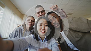 POV of asian girl holding smartphone taking selfie photos with cheerful multi-ethnic classmates and have fun at
