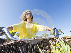 Pov of cheerful happy adult young caucasian woman with long blonde curly hair ride the bike in outdoor leisure activity - coloured