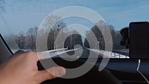 POV close-up shot, driver steering the car on magnificent winter road with smartphone navigation app slow motion.