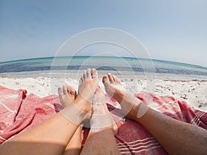 Pov of couple feet enjoying beach and sun in summer holiday vacation at the beach with calm sea fish eye background. People