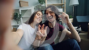 POV of cute couple taking selfie at home with new house keys showing thumbs-up