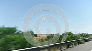 POV driving in countryside from car window past fields, trees and windmills in Larnaca, Cyprus