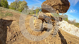 POV: Excavator arm scoops up a bucket full of soil and unloads it on trailer.