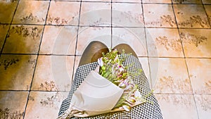 POV female laps with bouquet of pink flowers wrapped in craft paper. Alstroemerias. Femininity. Film grain texture. Soft