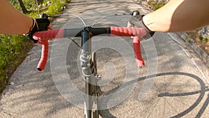 POV: First person shot of pedalling a bicycle up a hill in the sunny mountains.