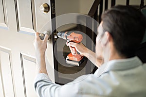 Pov of a handyman fixing door knob