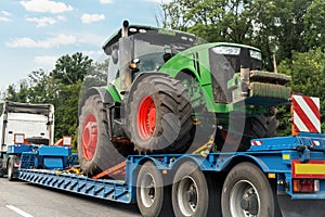 POV heavy industrial truck semi trailer flatbed platform transport one big modern farming tractor machine on common