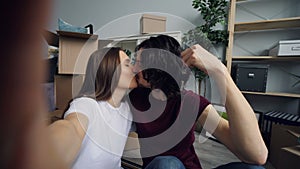 POV of husband and wife taking selfie with new flat keys kissing and posing