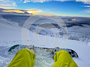 POV: Looking at sunset while sitting in fresh snow during a snowboarding trip photo