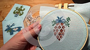 POV making cross stich in shape of pine tree cone. Christmas embroidery. Cross-stitch needlework on a hoop. Christmas