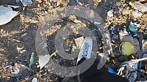 POV male feet in sneakers stepping on garbage at landfill. Legs of young man walking on junkyard at countryside. Trash
